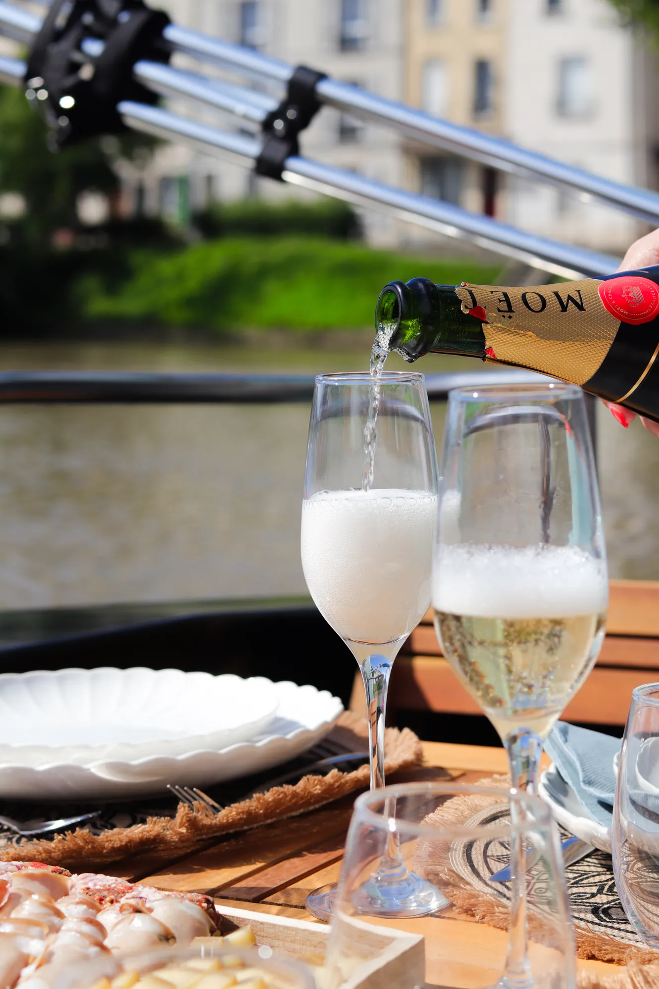 Table dressée à bord d'un bateau sur la Marne : assiettes, planche et coupes de champagne face à la rivière
