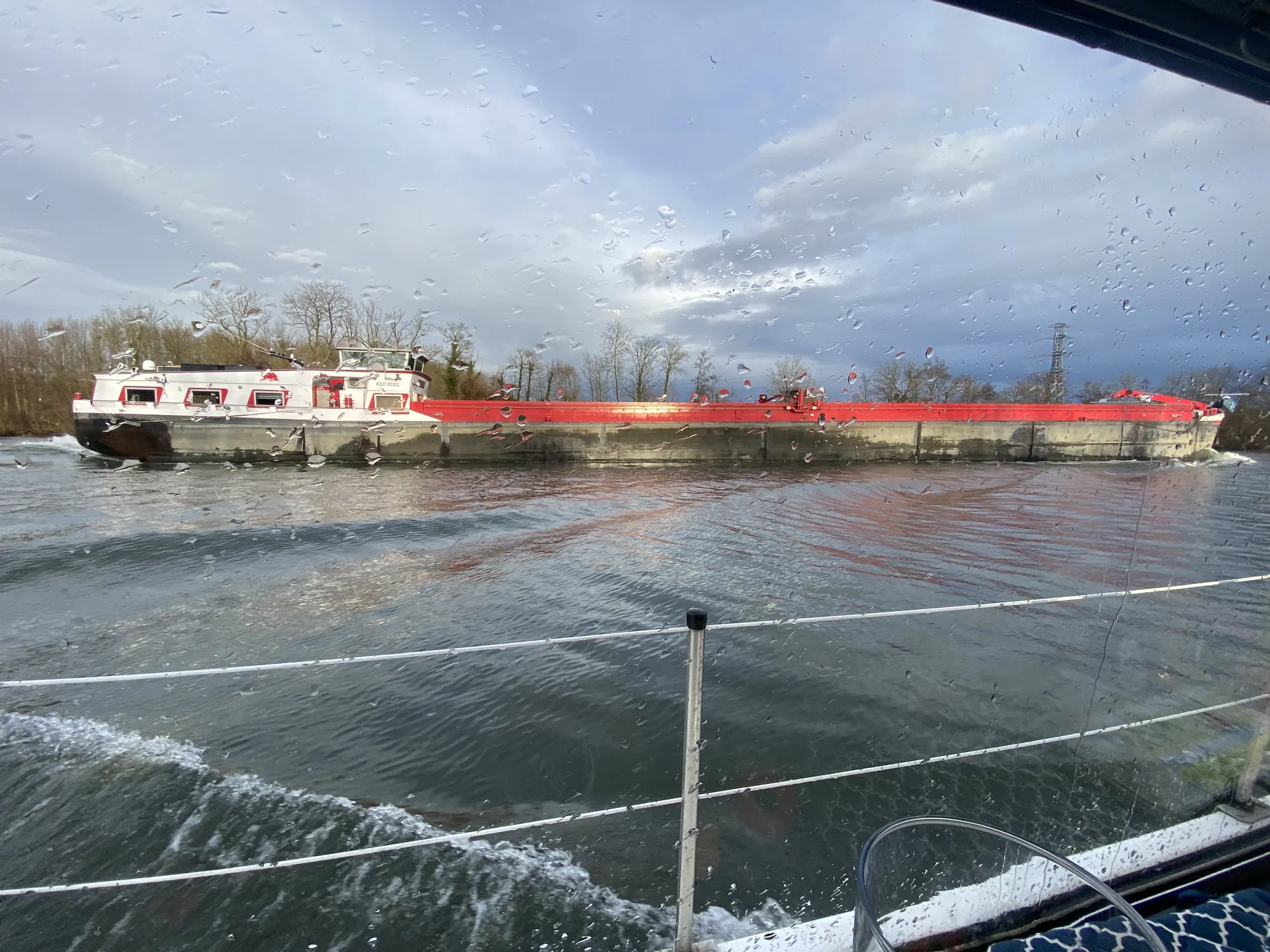 Péniche de commerce croisant sur la Marne, vue depuis le pont d'un bateau de promenade, berges boisées en arrière-plan