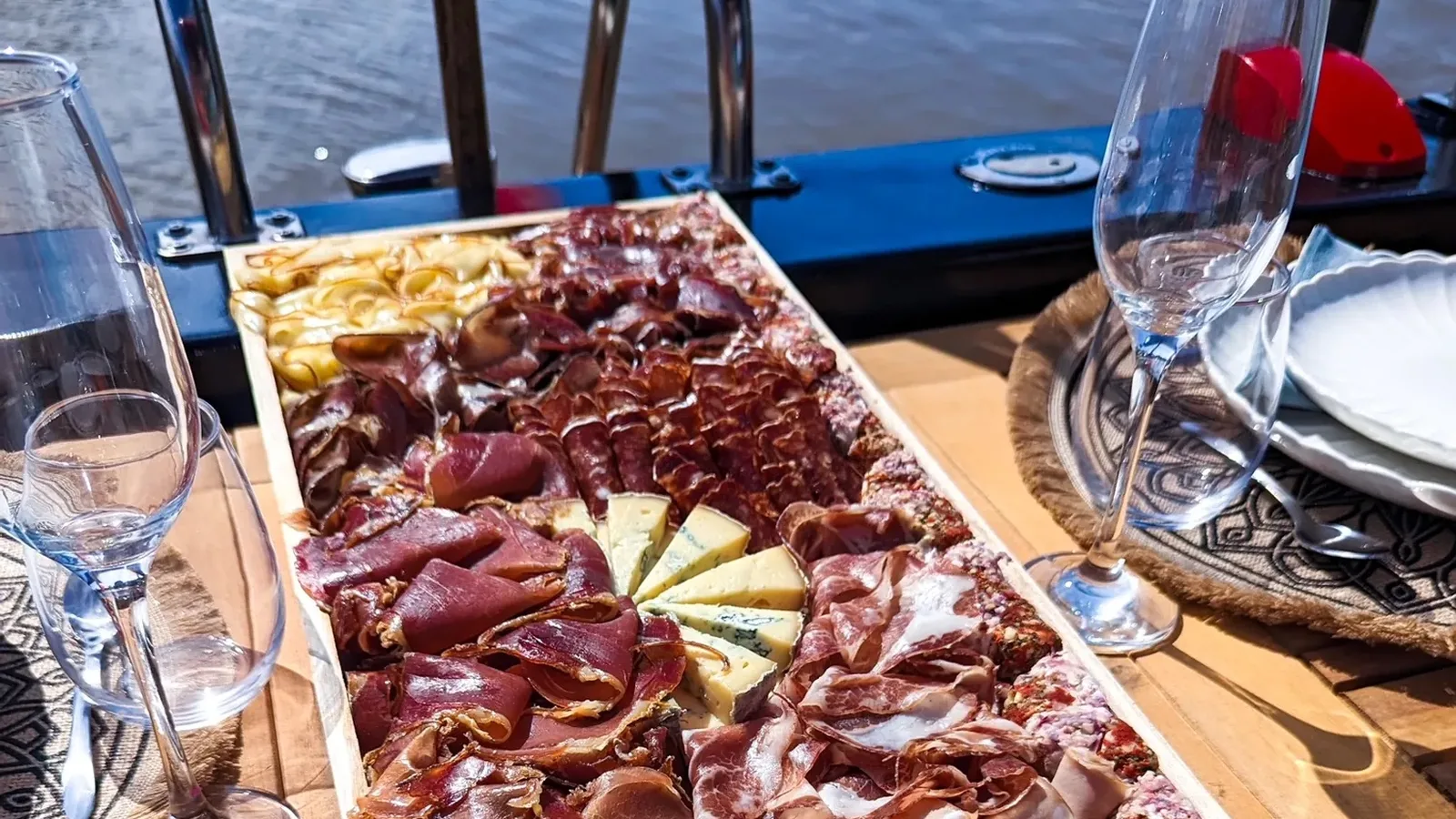Planche apéritive de produits locaux et flûtes à champagne servies à bord d'un bateau, face à la Marne